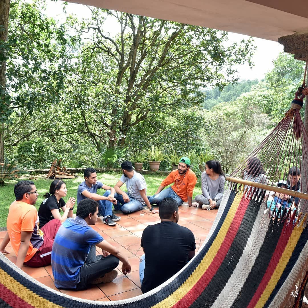A group sitting together on the porch beside a hammock