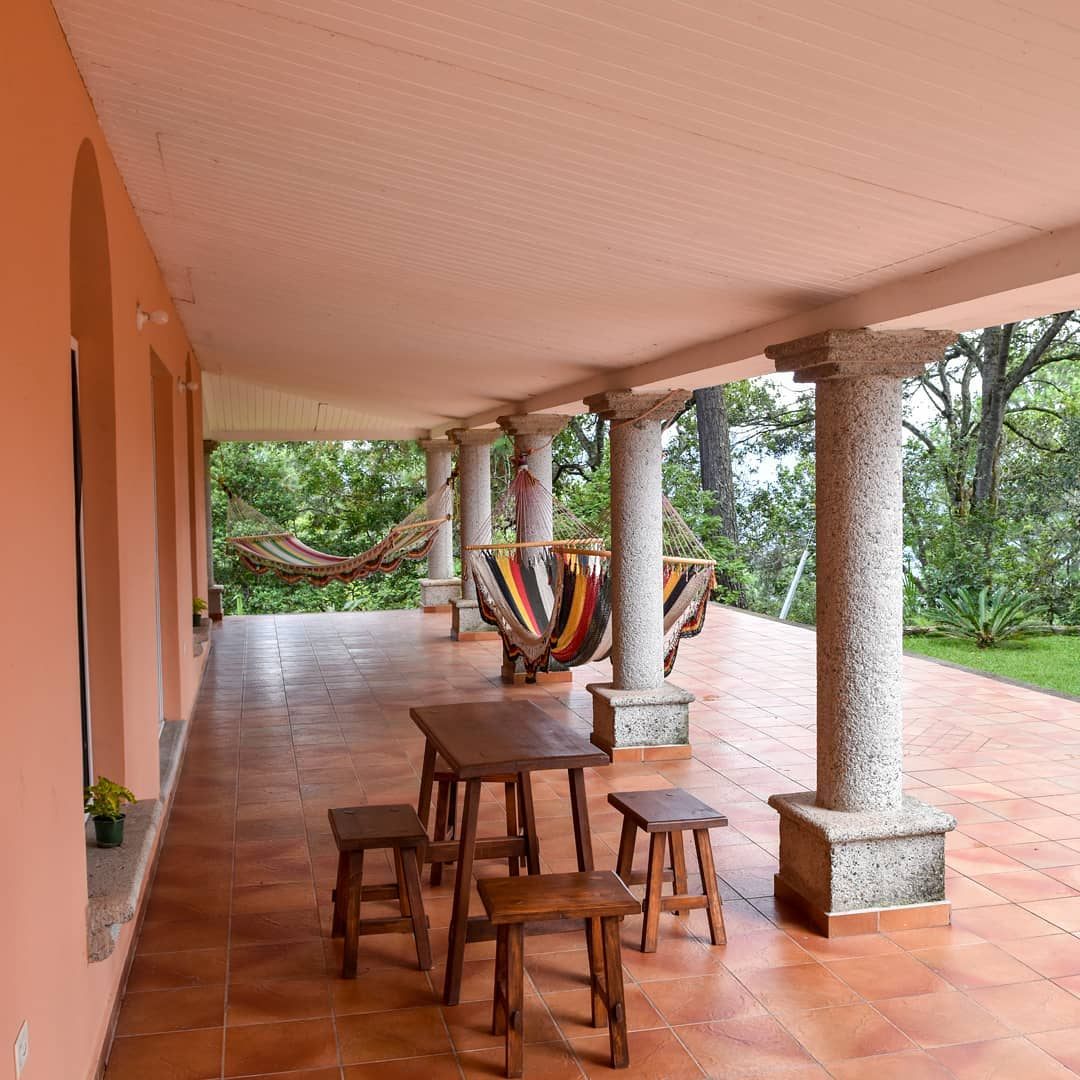 Long porch with granite columns, hammocks and a wooden table